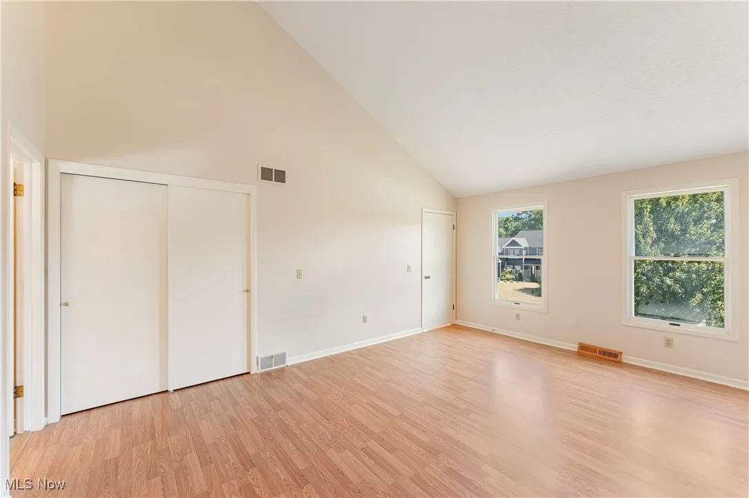 Unfurnished bedroom with high vaulted ceiling, light wood-type flooring, and a closet