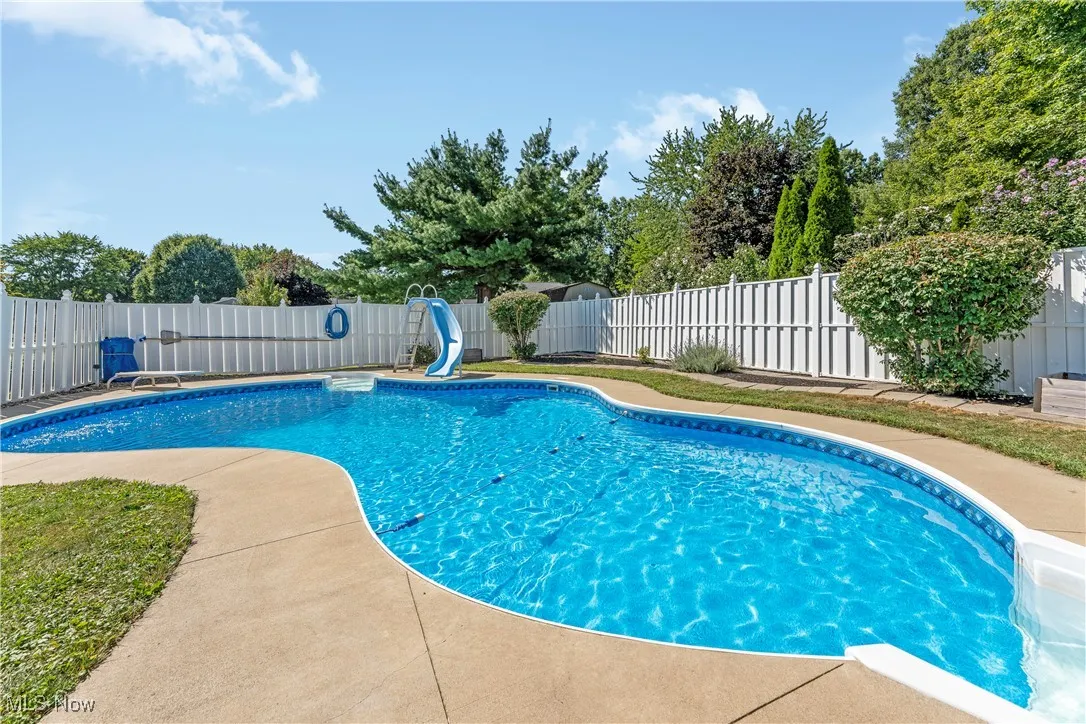 View of swimming pool featuring a water slide and a fenced backyard