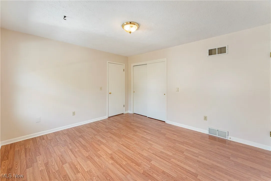 Spare room with light wood-type flooring and a textured ceiling