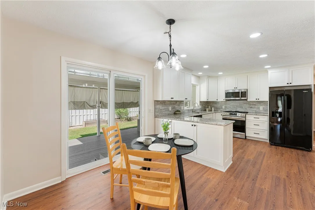 Kitchen featuring granite countertops appliances, white cabinetry, backsplash, and recessed lighting