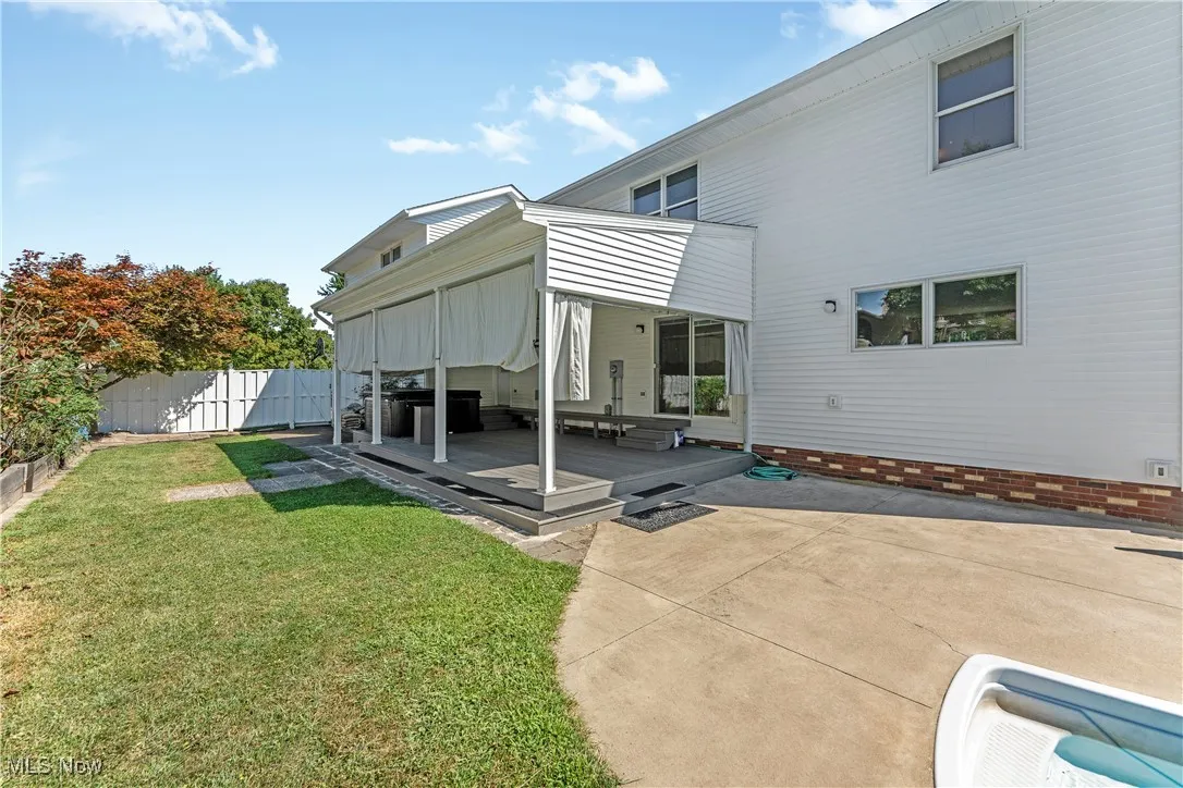 Back of property with a fenced backyard, a wooden deck, and a patio