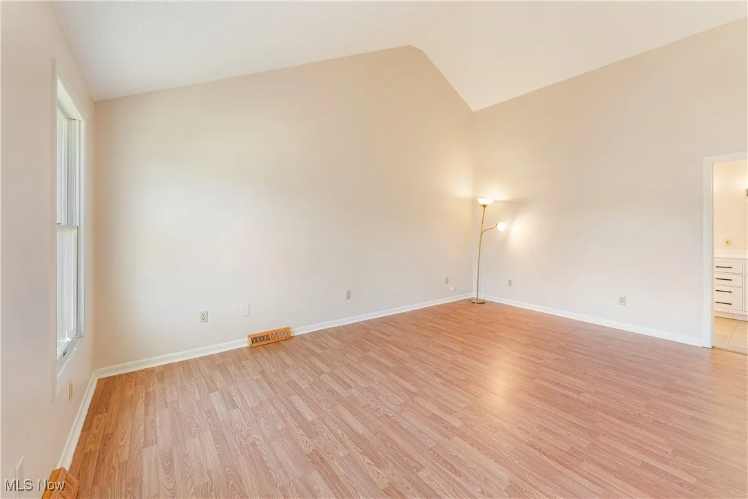 Primary Bedroom featuring light wood-type flooring and high vaulted ceiling