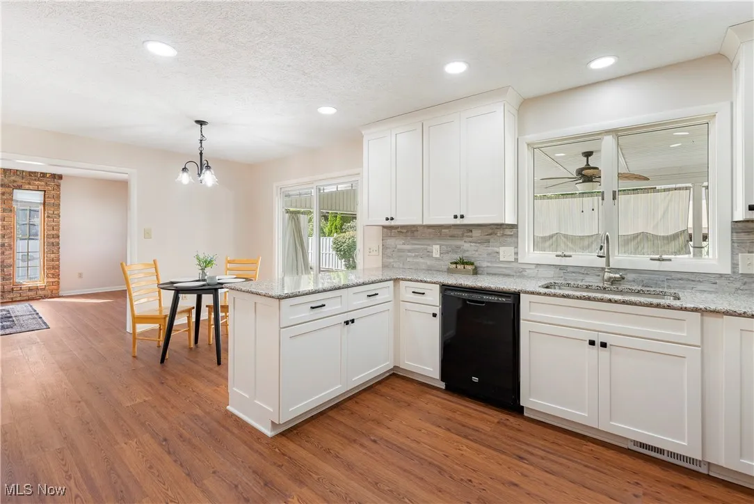 Kitchen featuring white cabinets, granite countertops, dishwasher, a textured ceiling, and pendant lighting