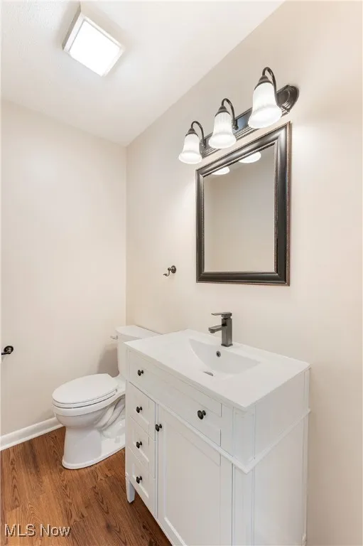 Half bathroom featuring vanity and dark wood-type flooring
