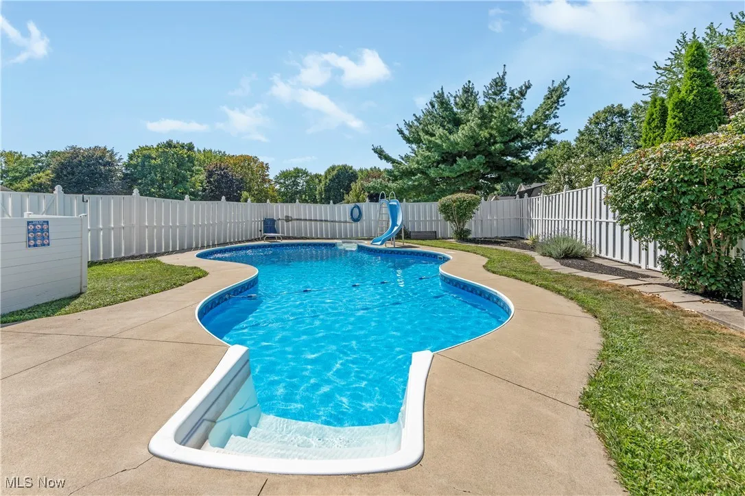 View of swimming pool featuring a water slide, a patio, and a fenced backyard