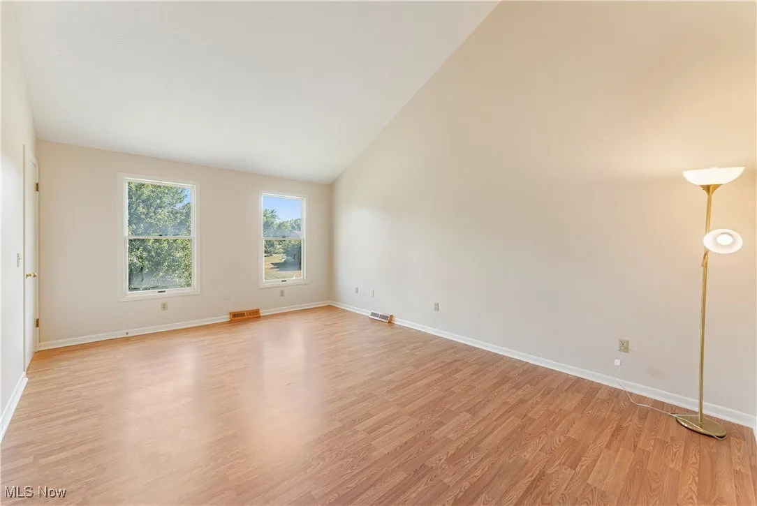Unfurnished room featuring light wood-style flooring and high vaulted ceiling