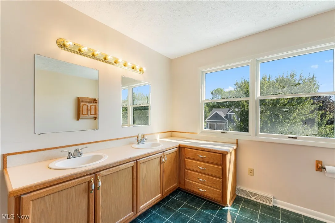 Bathroom featuring dark tile patterned floors, double vanity, and a textured ceiling