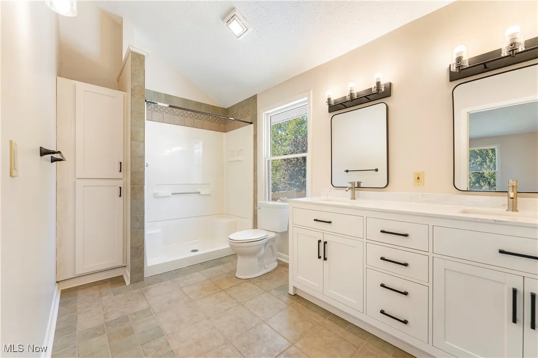 Bathroom with healthy amount of natural light, a walk in shower, and double vanity