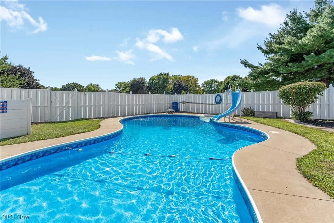 View of pool with a water slide, a fenced backyard, and a patio area