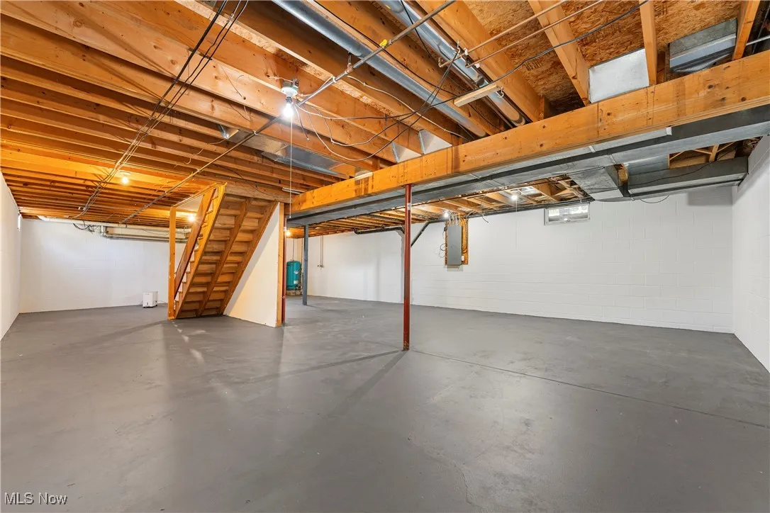 Unfinished below grade area with stairway and electric panel