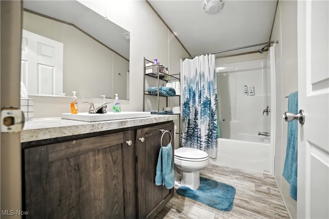 Full bath featuring shower / bathtub combination with curtain, vanity, and light wood finished floors