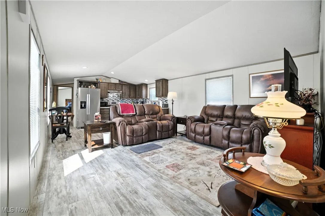 Living room featuring light wood-style floors, vaulted ceiling, and recessed lighting