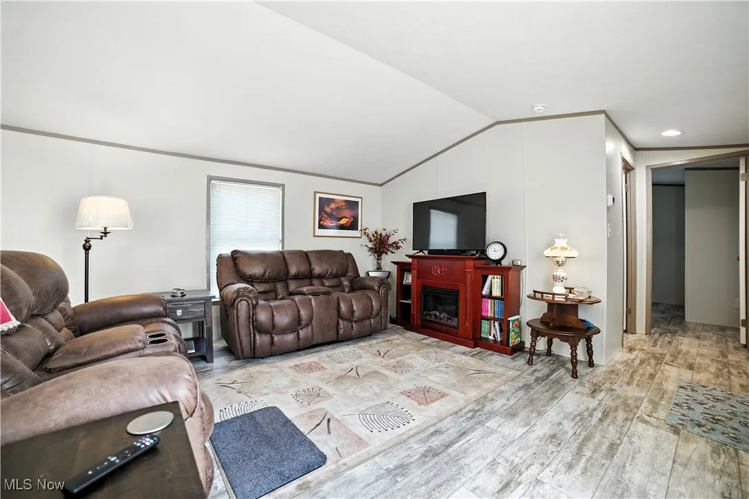Living room with lofted ceiling, a glass covered fireplace, and wood finished floors