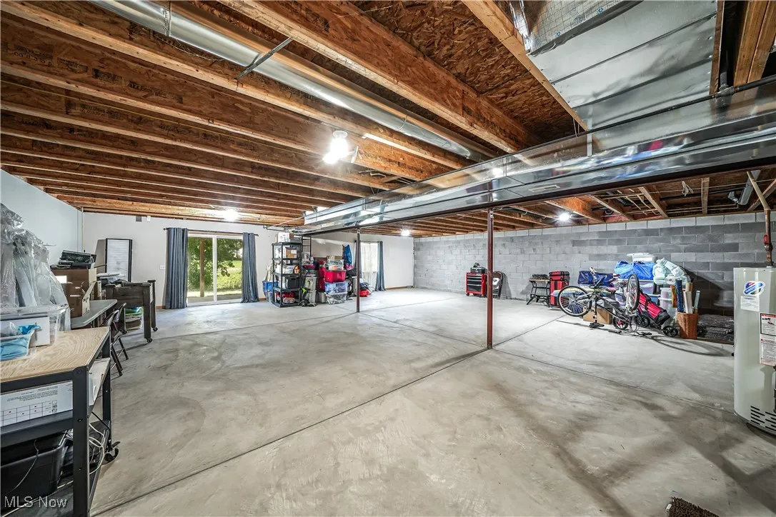 Basement featuring water heater and concrete block wall