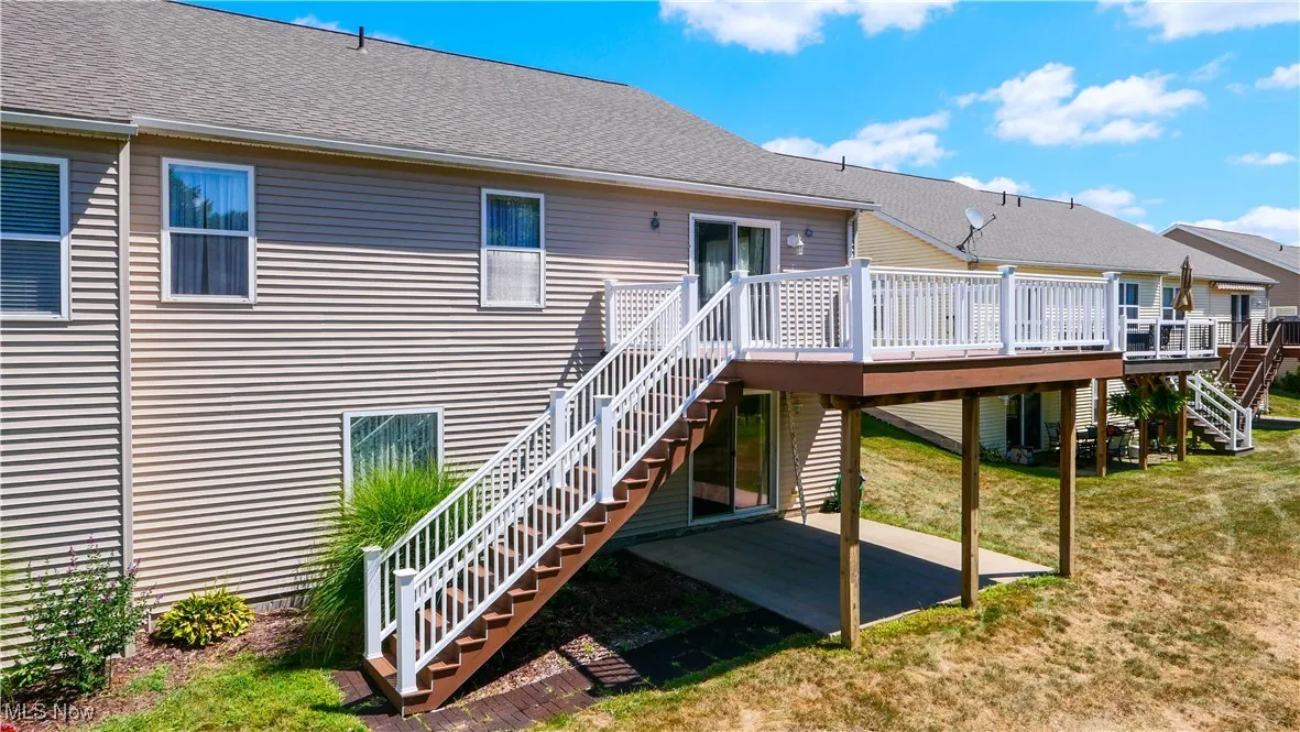 Back of house featuring stairway, a deck, and roof with shingles