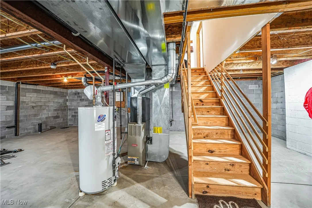 Unfinished below grade area with gas water heater and stairs
