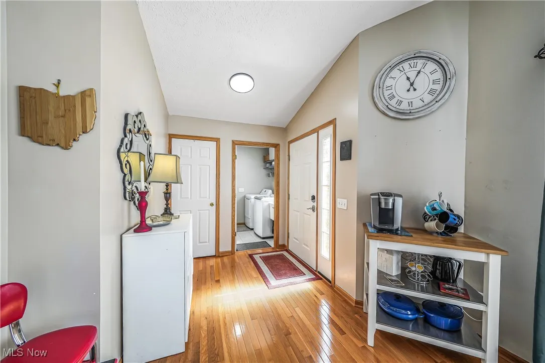 Doorway to outside with wood-type flooring and washer and clothes dryer