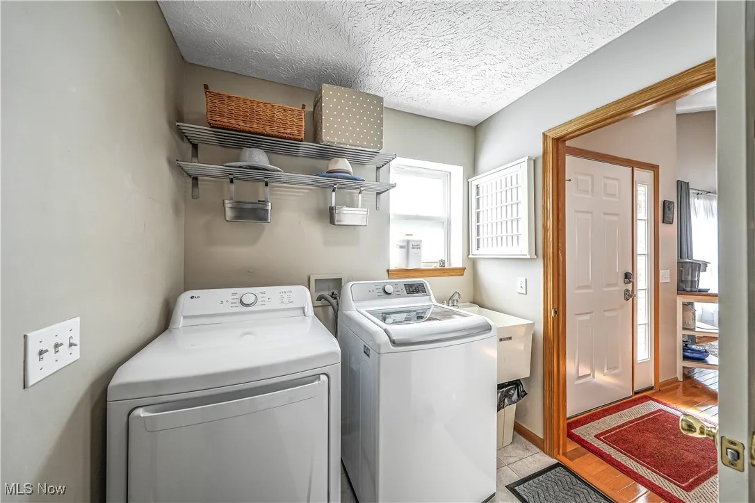 Washroom featuring a textured ceiling, washer and dryer, and light wood-type flooring