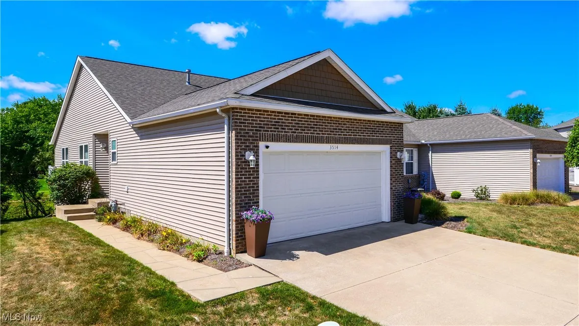 View of side of home featuring a yard, a garage, brick siding, and driveway