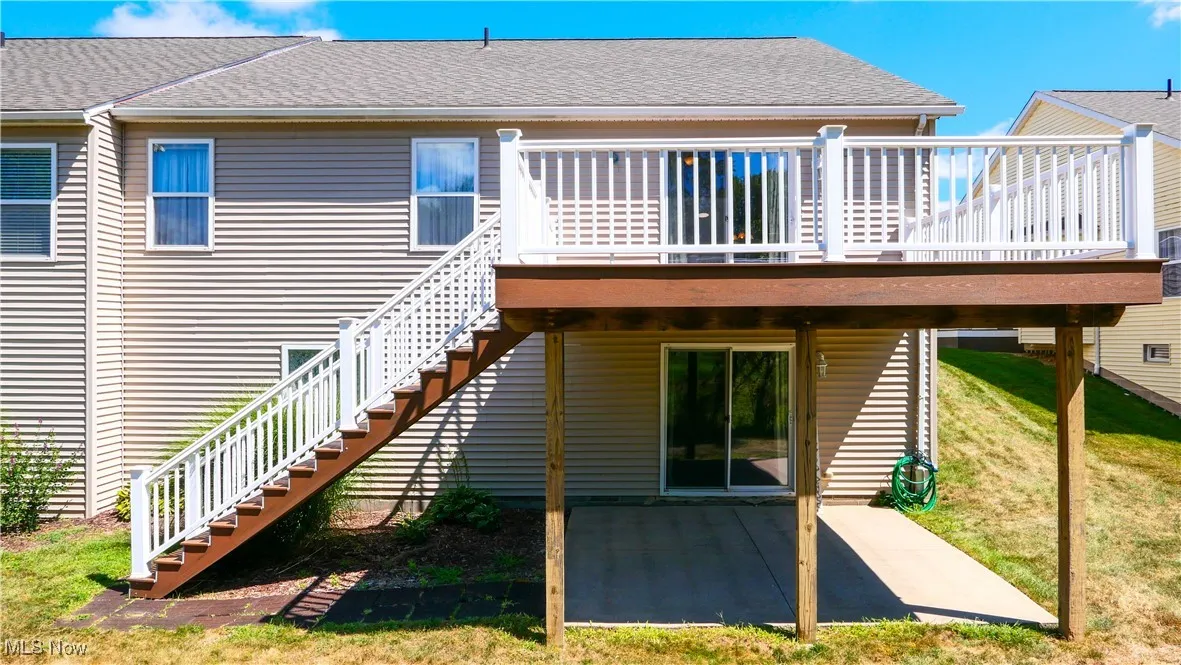 Rear view of property with stairway, a patio, a shingled roof, a lawn, and a wooden deck