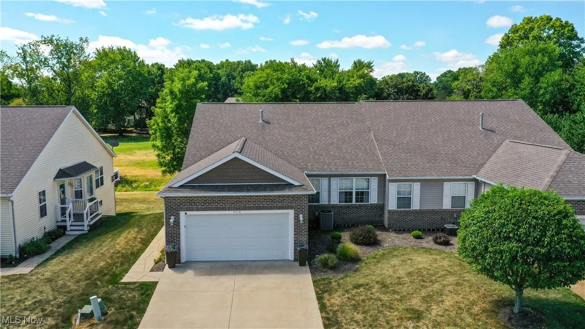 View of front of home featuring brick siding, a front lawn, a shingled roof, and concrete driveway