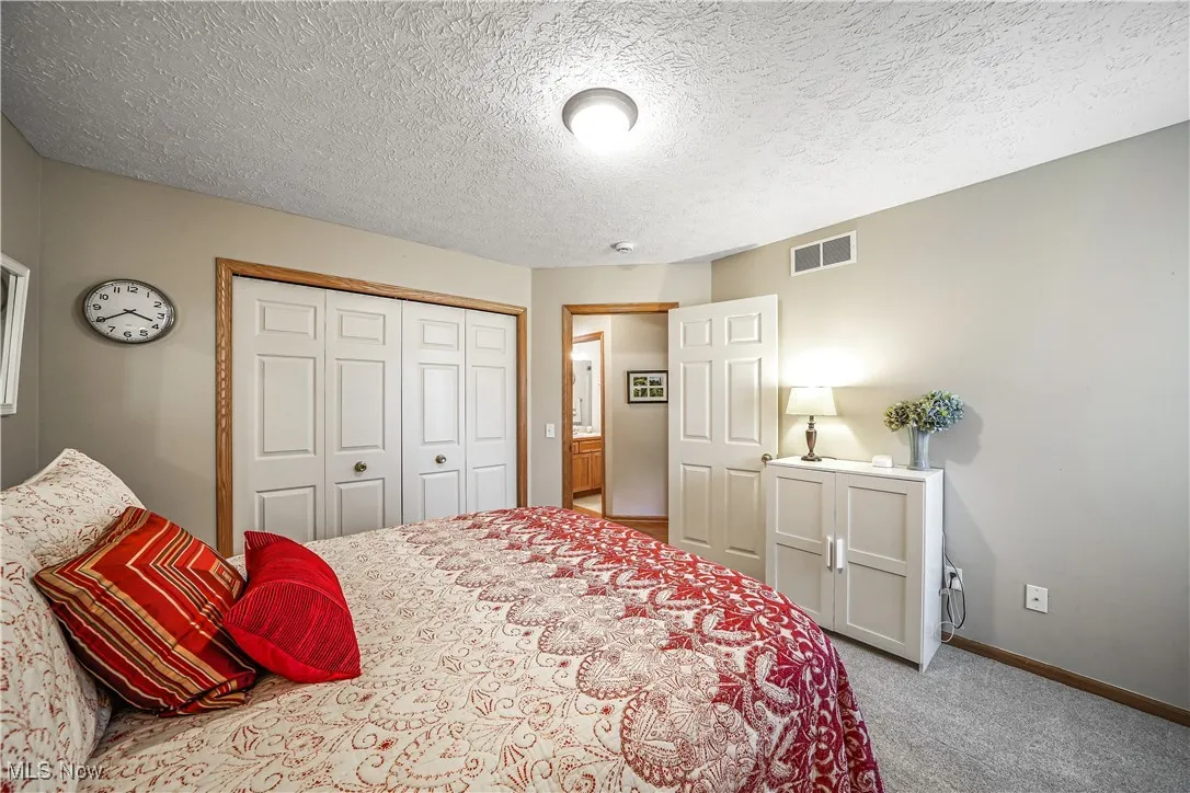 Carpeted bedroom featuring a textured ceiling and a closet