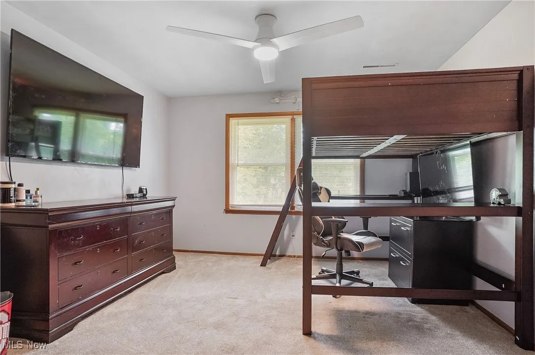 Bedroom featuring a desk, light carpet, and a ceiling fan