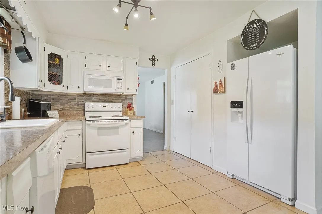 Kitchen with white cabinetry, white appliances, tasteful backsplash, and light countertops