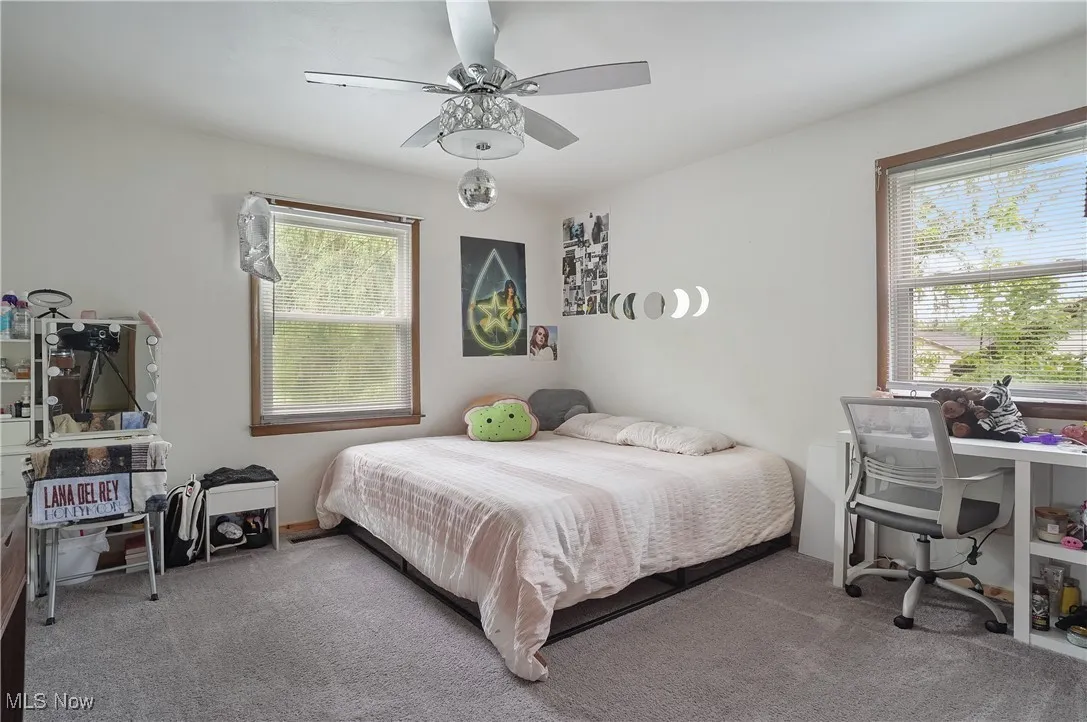Carpeted bedroom featuring a ceiling fan and an office area