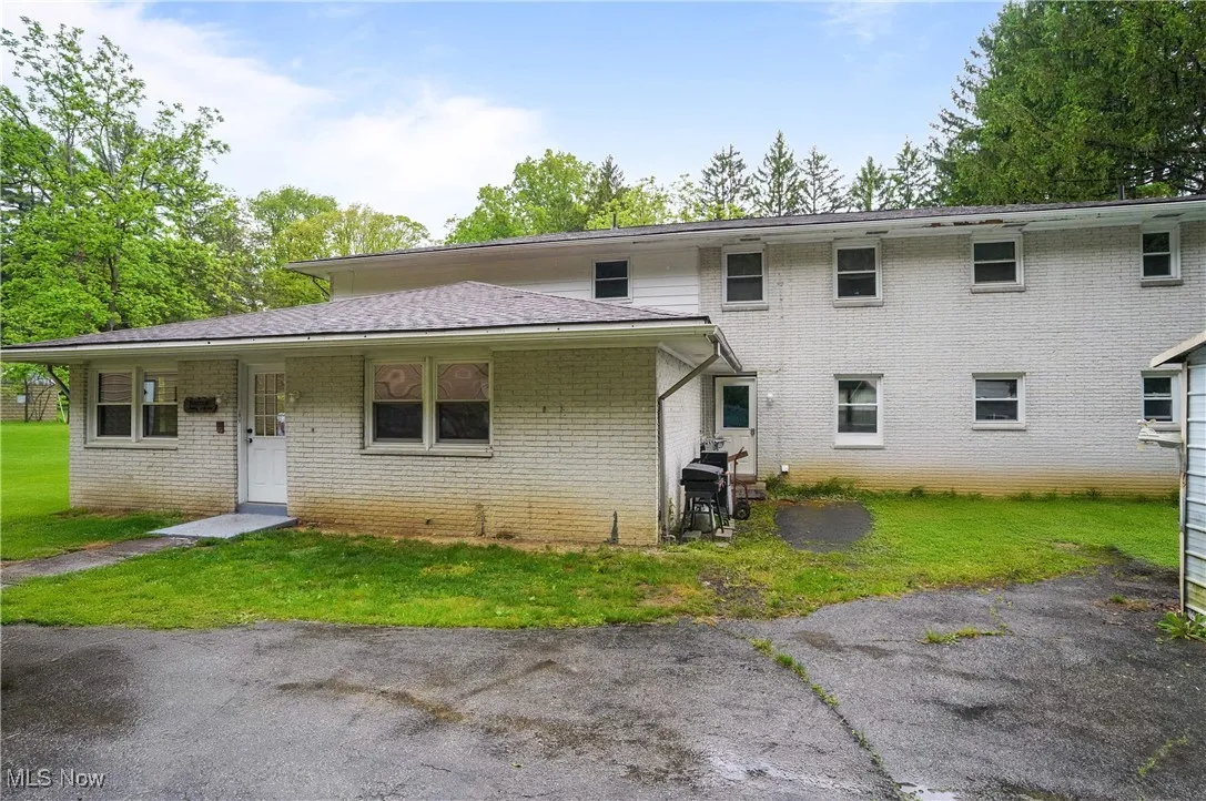 Back of house with a yard and brick siding