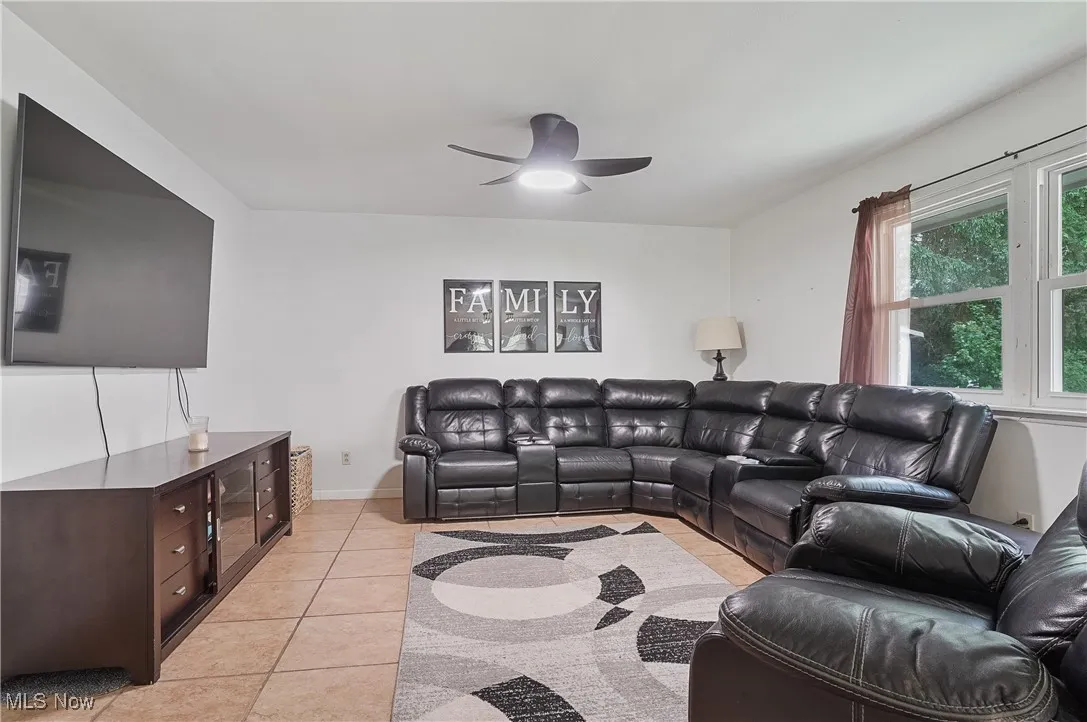 Living area with light tile patterned floors and a ceiling fan