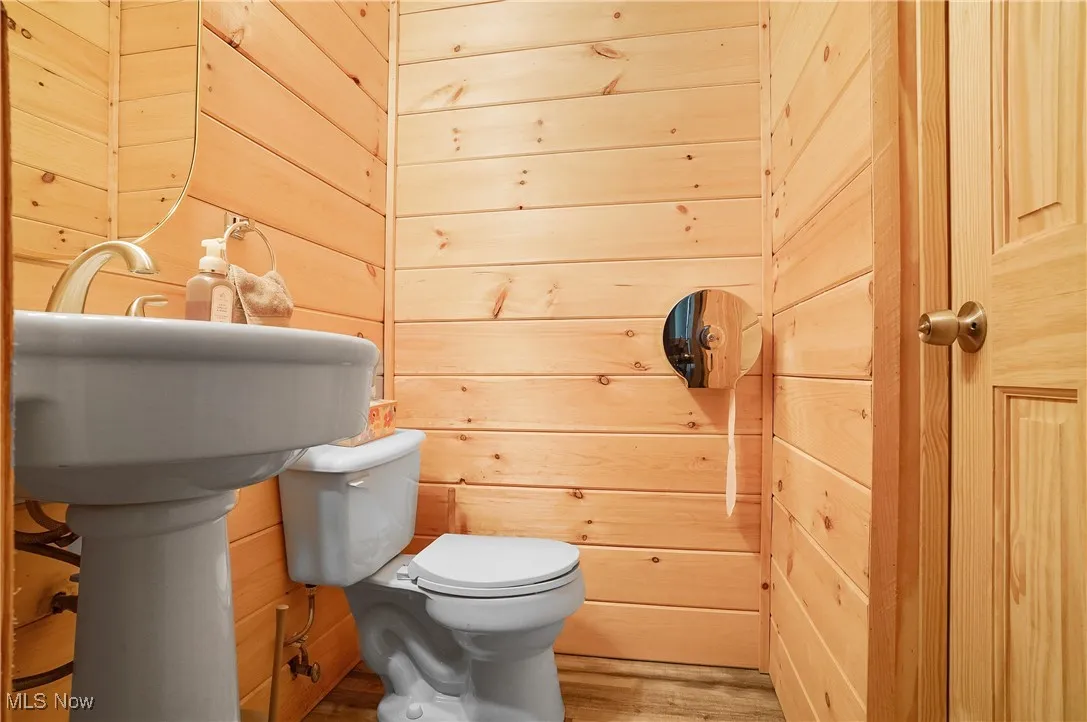 Half bath featuring wooden walls and wood finished floors