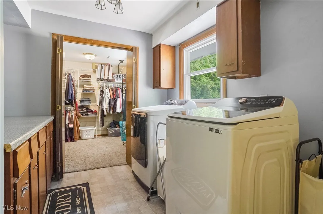 Laundry room featuring cabinet space, separate washer and dryer, and light colored carpet