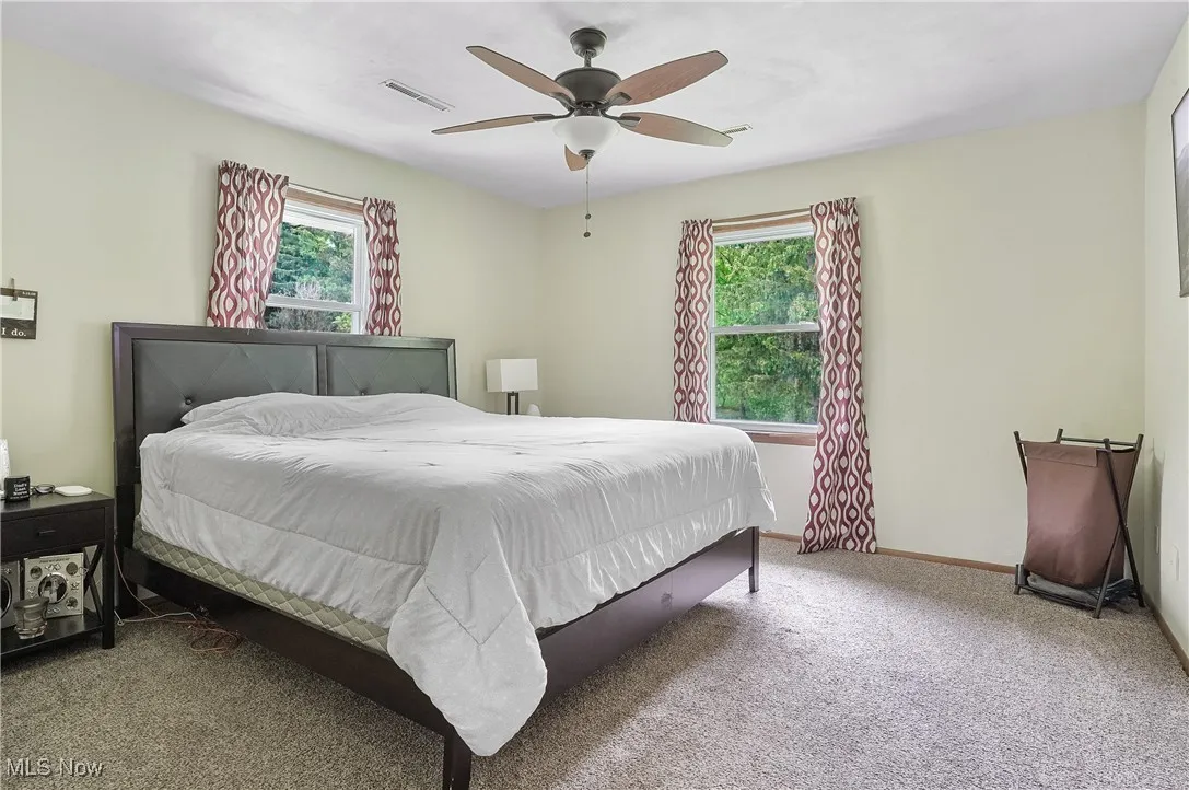 Bedroom with carpet flooring, multiple windows, and ceiling fan