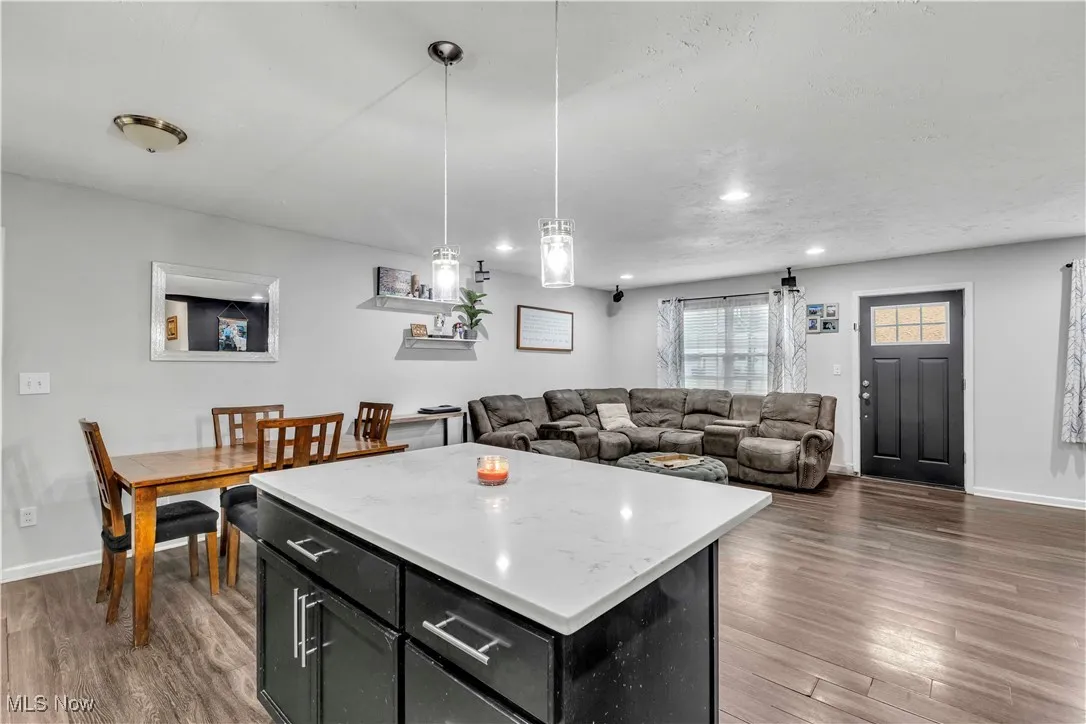 Kitchen featuring a kitchen island, dark cabinetry, decorative light fixtures, open floor plan, and dark wood-style floors