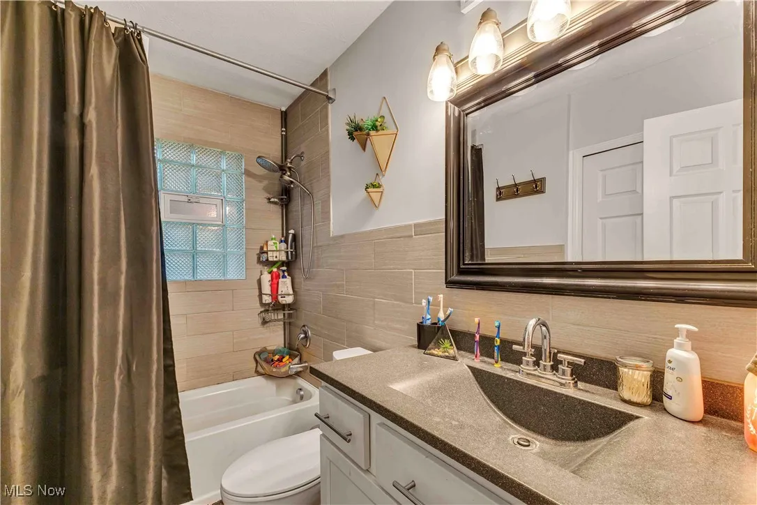 Full bathroom featuring tub/shower combo with tile surround, modern mirror and vanity.