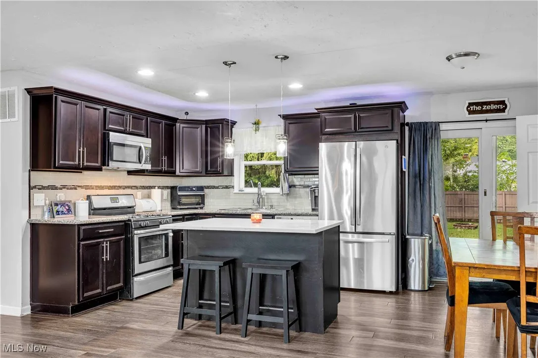 Kitchen with a center island, dark brown cabinets, appliances with stainless steel finishes, tasteful backsplash, and recessed lighting