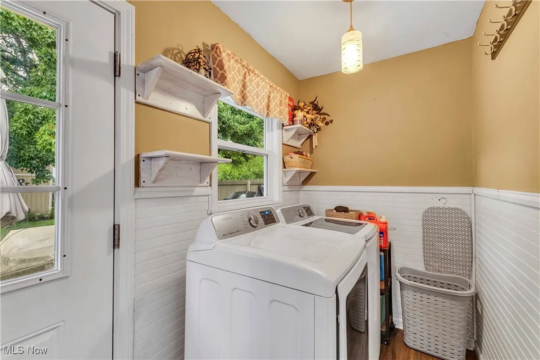 Laundry/mudroom between the garage, kitchen and backyard with wainscoting, floating shelves and modern light fixture.