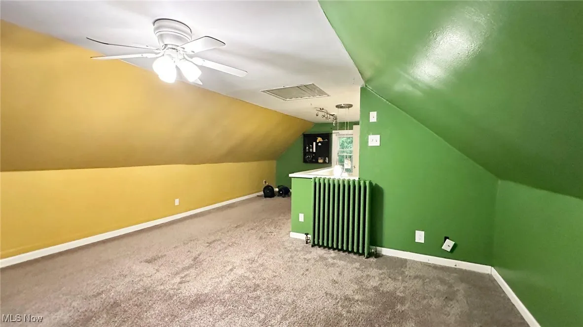 Bonus room featuring radiator, carpet flooring, lofted ceiling, and ceiling fan