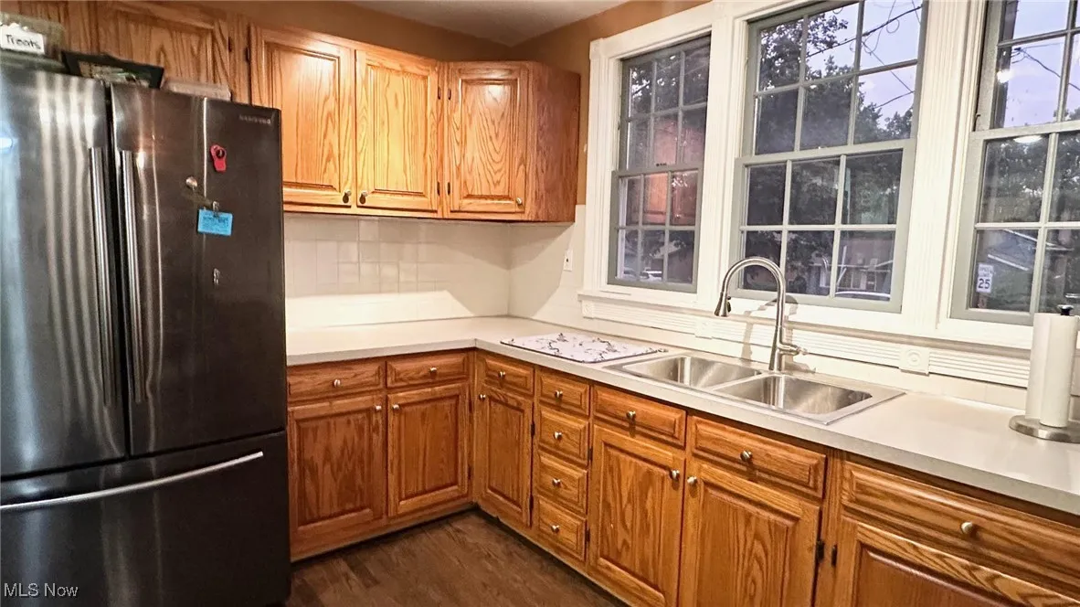 Kitchen featuring freestanding refrigerator, brown cabinets, light countertops, and wood floors