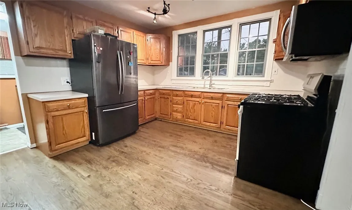 Kitchen featuring appliances with stainless steel finishes, light countertops, light wood finished floors, and brown cabinetry