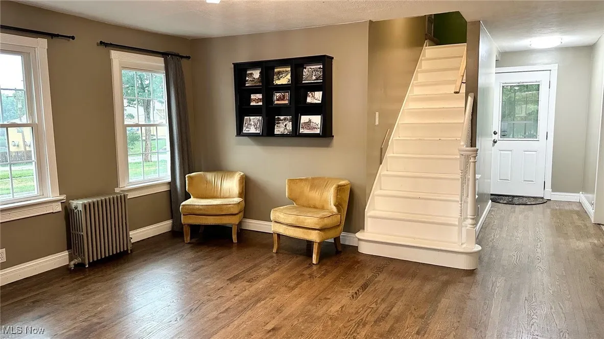 Living area with healthy amount of natural light, radiator, and dark wood-style flooring