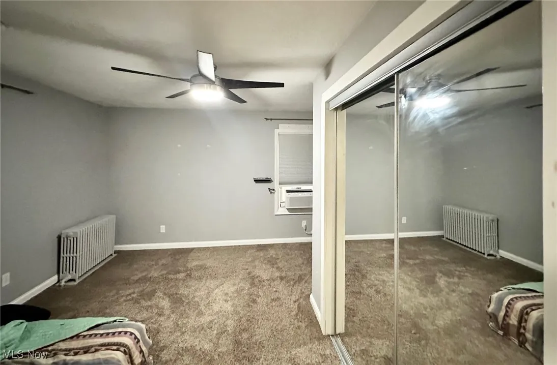 Bedroom featuring radiator heating unit, carpet, a closet, and ceiling fan