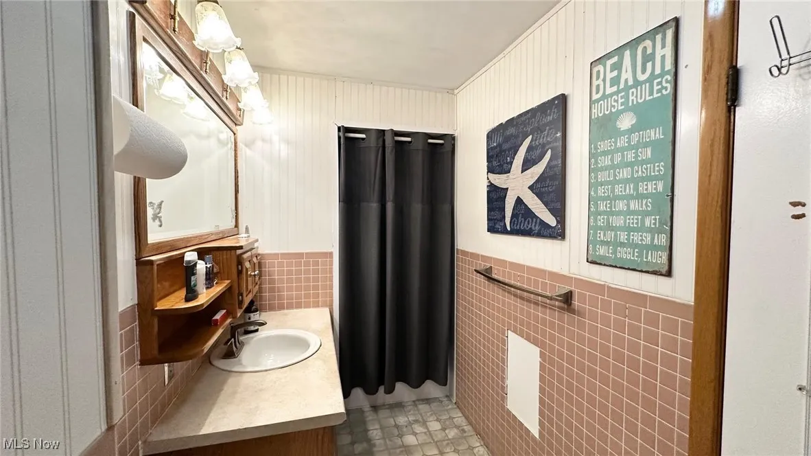 Bathroom with tile walls, a wainscoted wall, and vanity