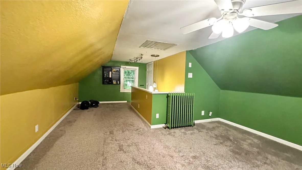 Bonus room with lofted ceiling, radiator heating unit, carpet, and a ceiling fan