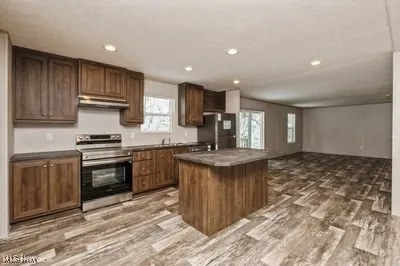 Kitchen with electric range, light wood finished floors, freestanding refrigerator, a kitchen island, and recessed lighting