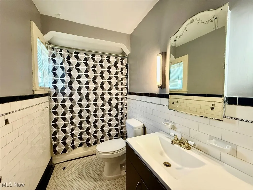 Full bathroom featuring light tile patterned flooring, tile walls, vanity, and a wainscoted wall