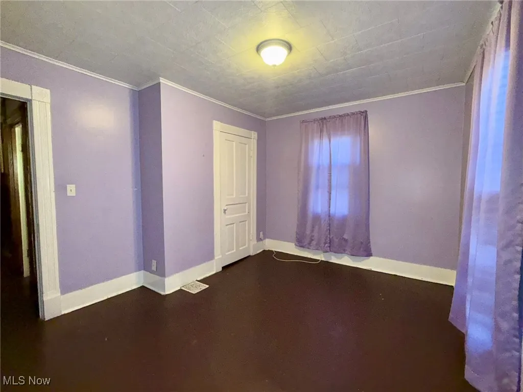 Bedroom with crown molding and dark wood-type flooring