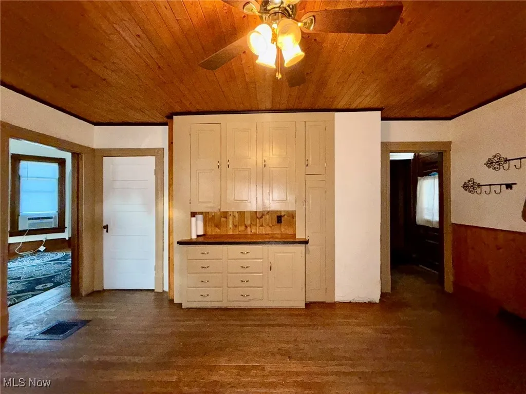 Kitchen with a wainscoted wall, wood walls, white appliances, light wood finished floors, and wood ceiling
