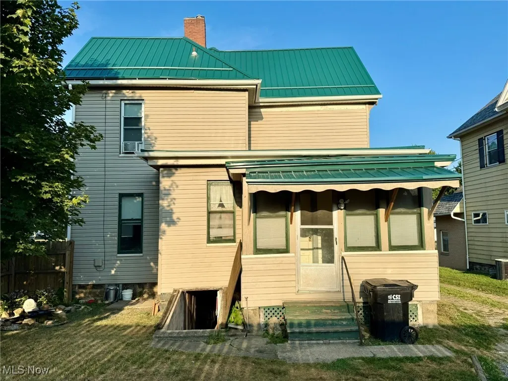 Back of house with a standing seam roof, a metal roof, and a chimney